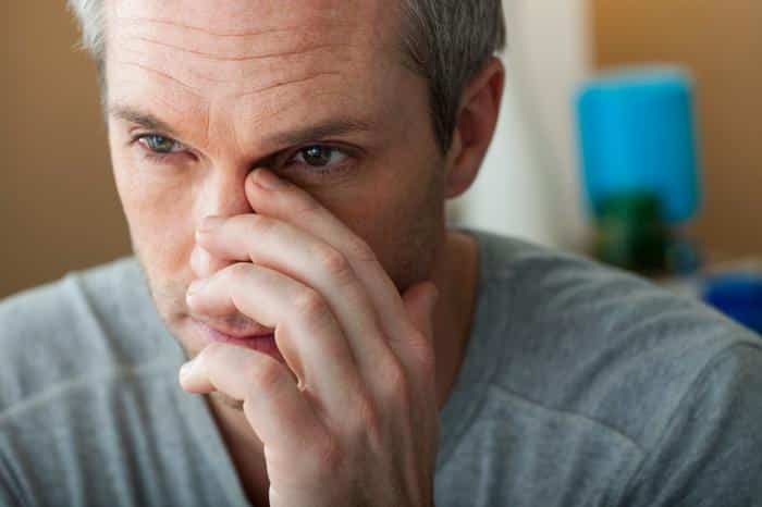 man with nose pain touching nose
