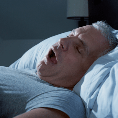 a man sleeping in bed with his mouth open, representing ENT specialist for snoring