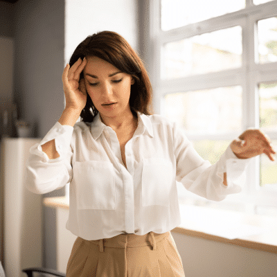 Woman holding her head, appearing off balance, representing balancing disorders
