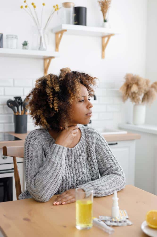 1760111477_woman-sore-throat-sititing-kitchen