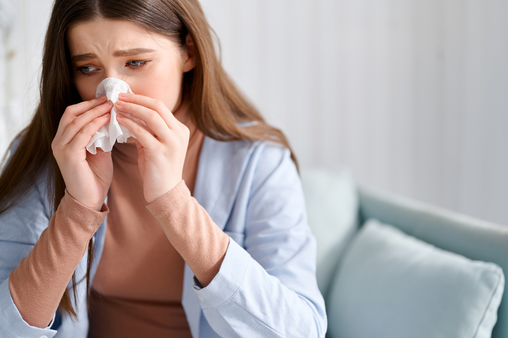 Woman blowing her nose while experiencing chronic sinus infection symptoms